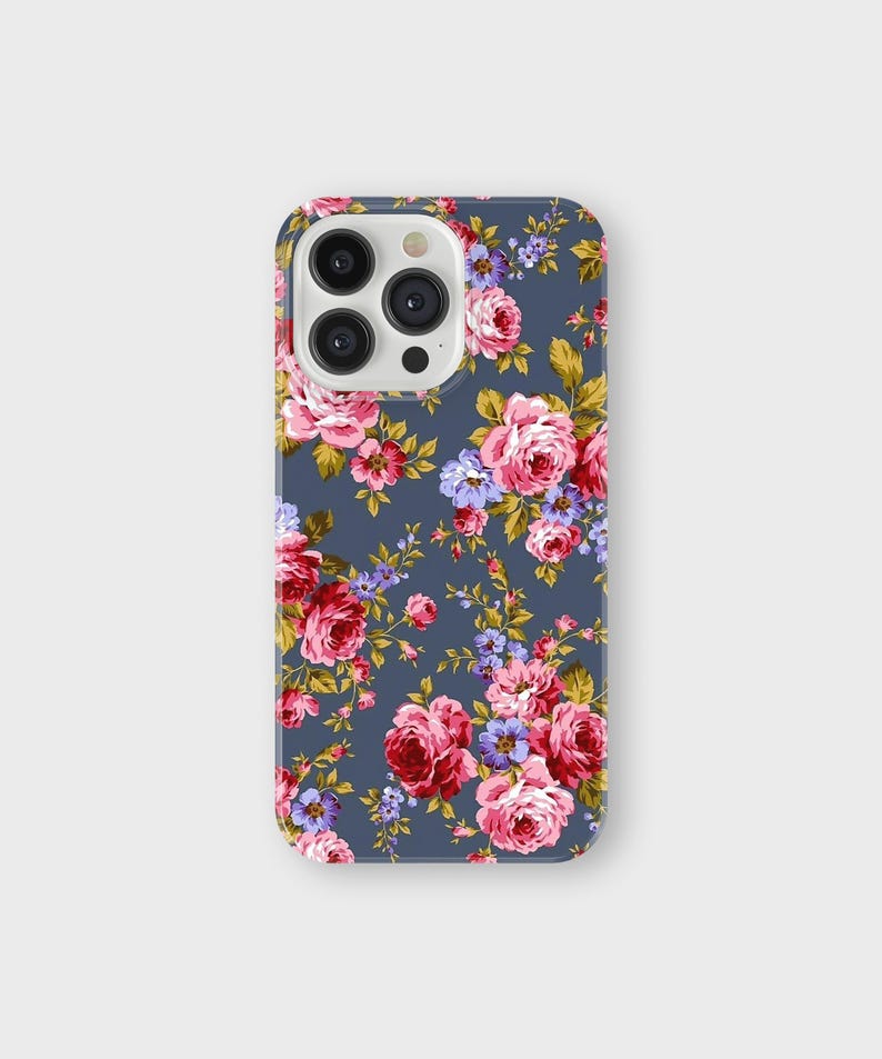 以下が含まれることがあります： 花柄のスマートフォンケース。ケースは、ピンク、赤、紫のバラと緑の葉の繰り返し模様のダークブルーの背景が特徴です。ケースは光沢のある仕上がりです。