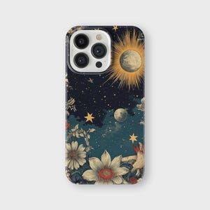 May include: A phone case with a dark blue background featuring a celestial design with stars, moons, and a sun. The design also includes floral elements in shades of red, yellow, and white.