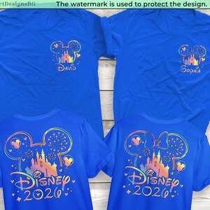 May include: Four blue t-shirts with Disney-themed designs. Two shirts have "David" and "Sophia" printed under a Mickey Mouse head and castle graphic. The other two shirts have "Disney 2026" printed on the back with a colorful castle design.