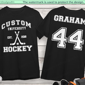 Può includere: T-shirt neri con testo e grafica bianchi. Una maglietta presenta "CUSTOM UNIVERSITY HOCKEY EST. 2018" con bastoni da hockey incrociati e un disco. L'altra maglietta mostra "GRAHAM 44".