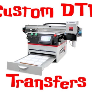 Op de afbeelding: Een witte en grijze DTF-printer met een open lade, die een lade met blanco witte transferbladen onthult. De printer heeft een zwart en rood bedieningspaneel en een zwarte slang die is aangesloten op de printkop. De tekst "Custom DTF Transfers" staat in rode letters boven de printer.