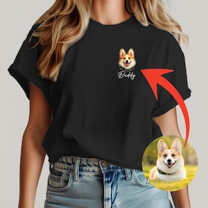 以下が含まれることがあります： 詳細なコーギー犬のイラストと名前「Buddy」が描かれた黒いTシャツ。犬の小さな丸い画像が右下にあります。犬は茶色、白、タン色です。