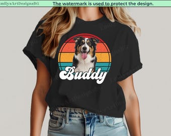 May include: Black t-shirt with a dog portrait and the name "Buddy" in a retro design. The dog is set against a circular background with orange, yellow, and teal stripes. The text "Buddy" is in a white, cursive font.