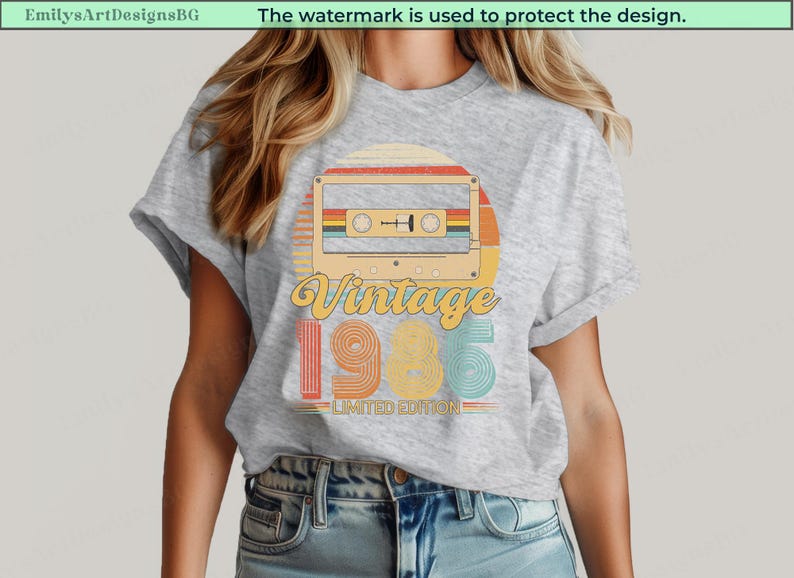 May include: A light gray t-shirt featuring a retro cassette tape design with the words "Vintage 1985 Limited Edition." The design incorporates a sunset color scheme with orange, yellow, and teal accents, evoking a nostalgic feel.