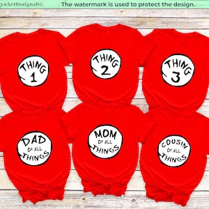 May include: Six red t-shirts with white circular designs. The shirts display the phrases "Thing 1", "Thing 2", "Thing 3", "Dad of All Things", "Mom of All Things", and "Cousin of All Things". The watermark "EmilysArtDesignsBG" is visible.