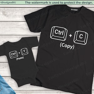 以下が含まれることがあります： 白い文字とコンピューターキーの画像が書かれた黒いTシャツと黒いベビーロンパース。Tシャツには「Ctrl + C（コピー）」、ロンパースには「Ctrl + V（貼り付け）」と書かれています。