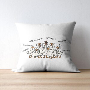 May include: White throw pillow featuring a cartoon illustration of several geese with the text "MRS.EMILY!" in speech bubbles. The geese are depicted in a playful style with orange beaks and feet.