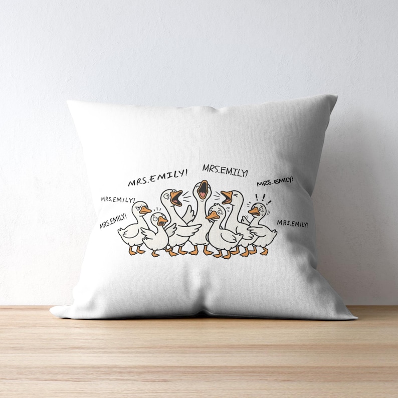 May include: White throw pillow featuring a cartoon illustration of several geese with the text "MRS.EMILY!" in speech bubbles. The geese are depicted in a playful style with orange beaks and feet.