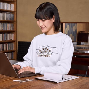 May include: White sweatshirt featuring a cartoon illustration of geese with speech bubbles. The geese are drawn in a simple style with brown outlines and details. Text includes "Mrs. Emily!" and other names.