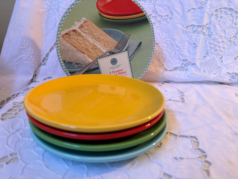 May include: A set of four ceramic plates in yellow, red, green, and blue. The plates are stacked on top of each other. The image shows a close-up of the plates.