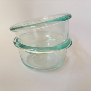 May include: Two clear glass bowls with a green rim stacked on top of each other.
