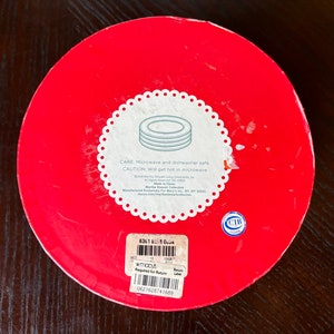 May include: Red round box with a white label that says "CARE: Microwave and dishwasher safe. CAUTION: Will get hot in microwave." The label also includes the text "Martha Stewart Collection" and "Made in China".