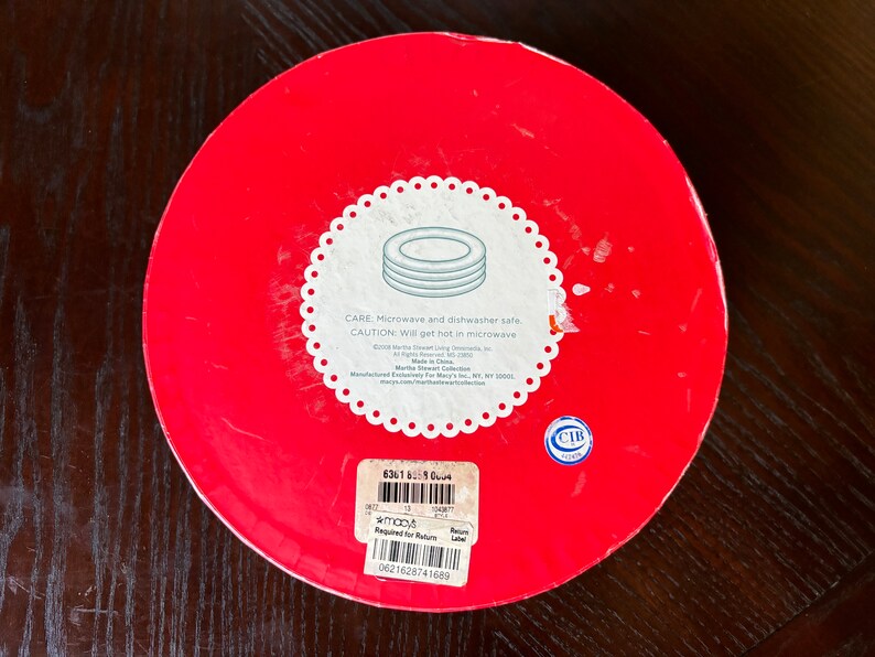 May include: Red round box with a white label that says "CARE: Microwave and dishwasher safe. CAUTION: Will get hot in microwave." The label also includes the text "Martha Stewart Collection" and "Made in China".