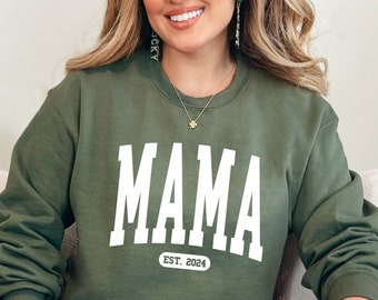 May include: A green sweatshirt with the word "MAMA" in white letters and the text "EST. 2024" underneath.
