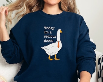 May include: A navy blue sweatshirt with a white goose wearing a tie and the text "Today I'm a serious goose".