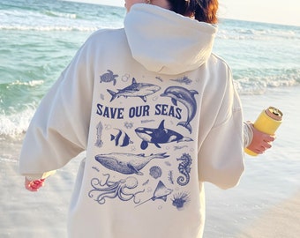May include: A cream-colored hoodie with a blue graphic print of various sea creatures and the text "SAVE OUR SEAS".