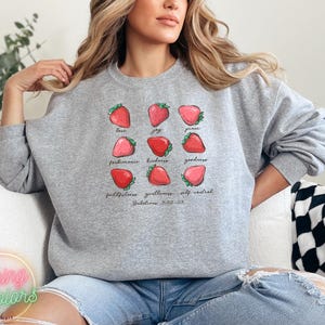 Puede incluir: Sudadera gris con un gr&aacute;fico de fresas y el texto "love, joy, peace, patience, kindness, goodness, faithfulness, gentleness, self-control, Galatians 5:22-23".