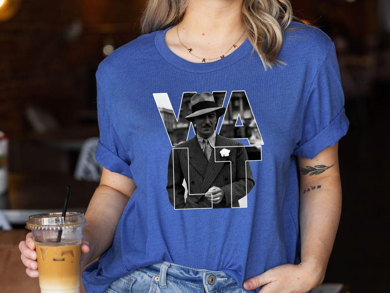 Puede incluir: Camiseta azul real con una imagen en blanco y negro de un hombre con traje y sombrero, con el nombre "WALT" en letras blancas. Las mangas est&aacute;n dobladas.