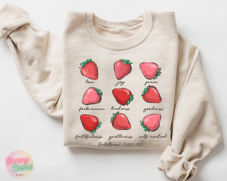 Puede incluir: Una sudadera beige con un gr&aacute;fico de fresas y el texto "love, joy, peace, forbearance, kindness, goodness, faithfulness, gentleness, self-control, Galatians 5:22-23".