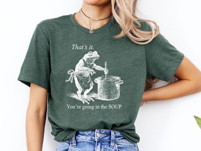May include: Dark green t-shirt with a humorous graphic of a frog stirring a pot of soup. The text above the frog reads "That's it." and below it says "You're going in the SOUP."