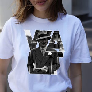 Puede incluir: Camiseta blanca con una imagen en blanco y negro de un hombre con traje y sombrero, con la palabra "WALT" superpuesta en letras blancas. La imagen est&aacute; centrada en la camiseta.