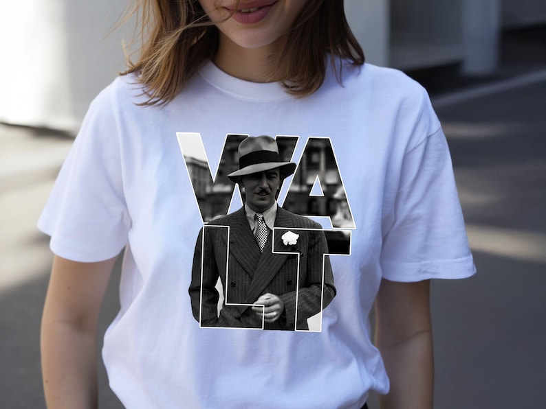 Puede incluir: Camiseta blanca con una imagen en blanco y negro de un hombre con traje y sombrero, con la palabra "WALT" superpuesta en letras blancas. La imagen est&aacute; centrada en la camiseta.