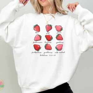 Puede incluir: Sudadera blanca con un gr&aacute;fico de fresas y el texto "love, joy, peace, forbearance, kindness, goodness, faithfulness, gentleness, self-control, Galatians 5:22-23".