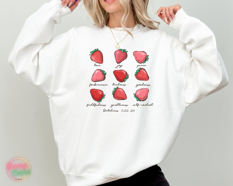 Puede incluir: Sudadera blanca con un gr&aacute;fico de fresas y el texto "love, joy, peace, forbearance, kindness, goodness, faithfulness, gentleness, self-control, Galatians 5:22-23".