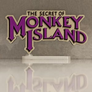 Könnte beinhalten: Ein lila-cremefarbenes Schild mit dem Text "THE SECRET OF MONKEY ISLAND" in einer stilisierten Schriftart. Das Schild ist auf einem transparenten, rechteckigen Sockel montiert. Der Hintergrund ist hellgrau.