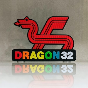 May include: A red dragon logo with black outlines and a wing design. The logo sits atop a black rectangle with the word "DRAGON 32" in rainbow colors. The image is reflected below.
