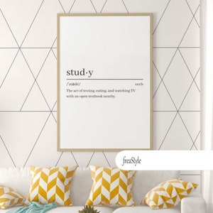 Puede incluir: Una impresión enmarcada con una definición de la palabra "study" como el acto de enviar mensajes de texto, comer y ver televisión con un libro abierto cerca. La impresión está colgada en una pared blanca con un patrón geométrico. Un sofá blanco con almohadas de tiro con estampado de chevron amarillo se encuentra frente a la pared. Una mesa de café de vidrio con una base de metal dorado se encuentra frente al sofá.