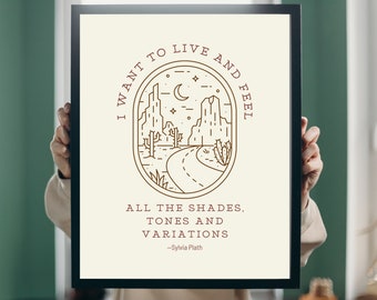 Puede incluir: Un cuadro enmarcado con una ilustración de paisaje desértico en líneas marrones sobre un fondo blanquecino. La obra de arte incluye el texto "I WANT TO LIVE AND FEEL" y "ALL THE SHADES, TONES AND VARIATIONS - Sylvia Plath."