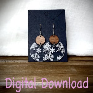 May include: A pair of snowflake earrings with a clear acrylic base and a wood accent. The earrings are on a black display card with the text "Digital Download".
