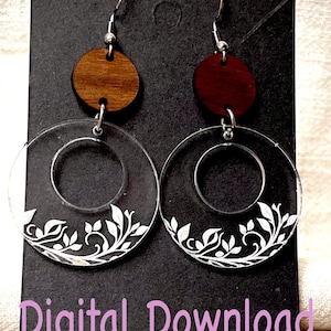 May include: A pair of earrings featuring a clear acrylic circle with a white floral design and a wooden circle on top. The wooden circles are brown and red.