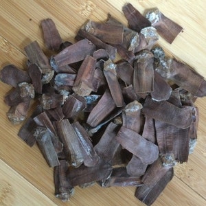 May include: A pile of brown, dried pine cone scales. The scales are various sizes and shapes, with some having a slightly lighter color.