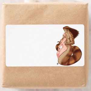 May include: A white rectangular sticker on a brown package features a fantasy illustration. The artwork depicts a humanoid figure with snake-like features embracing a blonde-haired person. The figures are in shades of brown, tan, and pink.