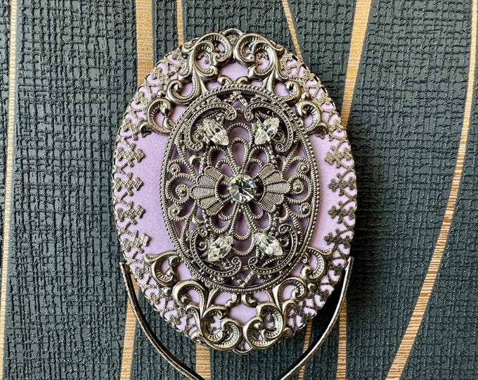 Small Antique Mirror Decorated with Delicate Transparent Stones on a Purple Background