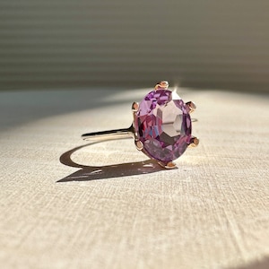 May include: A purple gemstone ring with a gold band and a prong setting.
