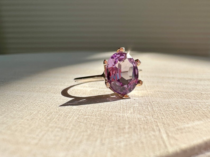 May include: A purple gemstone ring with a gold band and a prong setting.