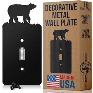 May include: A black metal light switch wall plate featuring a silhouette of a bear standing on grass at the top. The product is made of 18 gauge steel with a powder coat finish and includes two black mounting screws for installation.