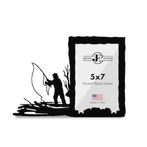 May include: A black metal portrait photo frame with a 5x7 inch display area. The frame features a silhouette cutout of a person fishing with a rod and line. The text on the frame reads Metal JE3 Works, 5x7 Portrait Photo Frame, and Made in USA.