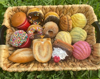 Peut inclure: Un panier en osier rempli de mini-sacs à main colorés et à motifs en forme de beignets, de pâtisseries et de pains. Les sacs à main sont en tissu et ont une variété de textures.