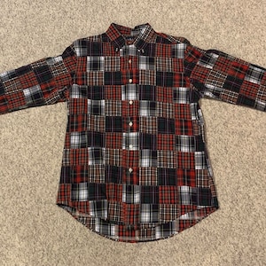 Może przedstawiać: Koszula z długim rękawem zapinana na guziki z patchworkowym wzorem w czarno-czerwono-białe kraty.