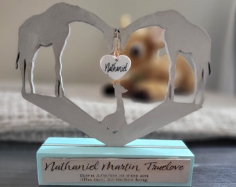 May include: A silver metal giraffe heart-shaped sculpture with a small heart charm that says "Nathaniel". The sculpture is on a light blue wooden base with the text "Nathaniel Martin Truelove Born 5/9/08 at 2:04 am 9lbs 6oz, 25 inches long".