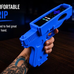 K&ouml;nnte beinhalten: Ein leuchtend blauer Fernbedienungshalter aus Kunststoff in Pistolenform mit einer schwarzen Fernbedienung im oberen Schlitz. Der Text auf dem Bild lautet 3 COMFORTABLE GRIP Designed to feel great in your hand.