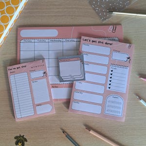 Op de afbeelding: Roze en grijze printbare plannerpagina's met een weekkalender, een dagelijkse to-dolijst en een gewoontetracker. De pagina's bevatten de tekst "Let's get shit done!" en "You've got this!"