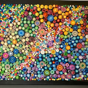 May include: A colorful abstract art piece made of paper circles of various sizes and colors. The circles are arranged in a swirling pattern on a black background.