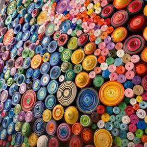 May include: A colorful wall art piece made of rolled paper circles in various sizes and colors. The circles are arranged in a pattern, creating a visually appealing and textured surface.
