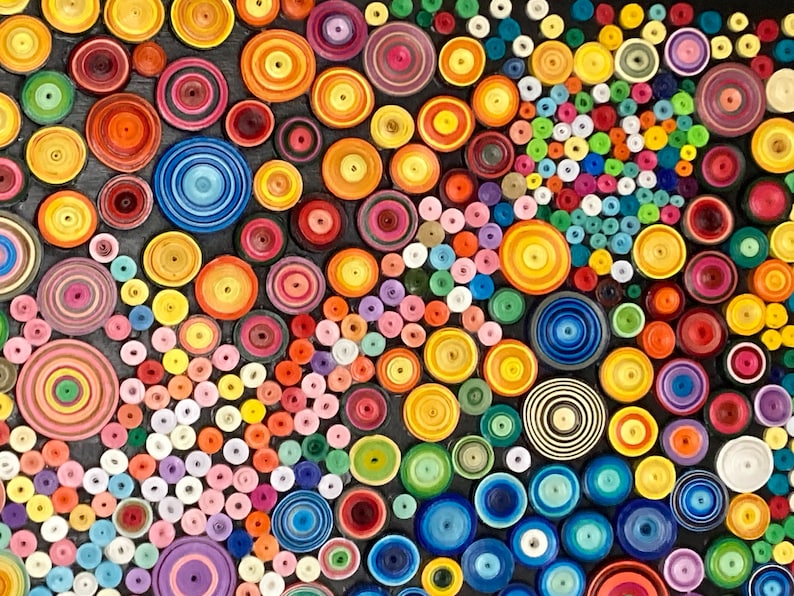 May include: A colorful abstract art piece made of paper circles of various sizes and colors. The circles are arranged in a swirling pattern, creating a sense of movement and energy.