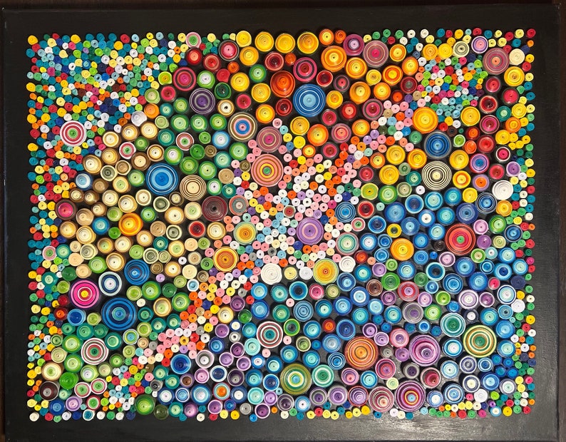 May include: A colorful abstract art piece made of paper circles of various sizes and colors. The circles are arranged in a swirling pattern on a black background.